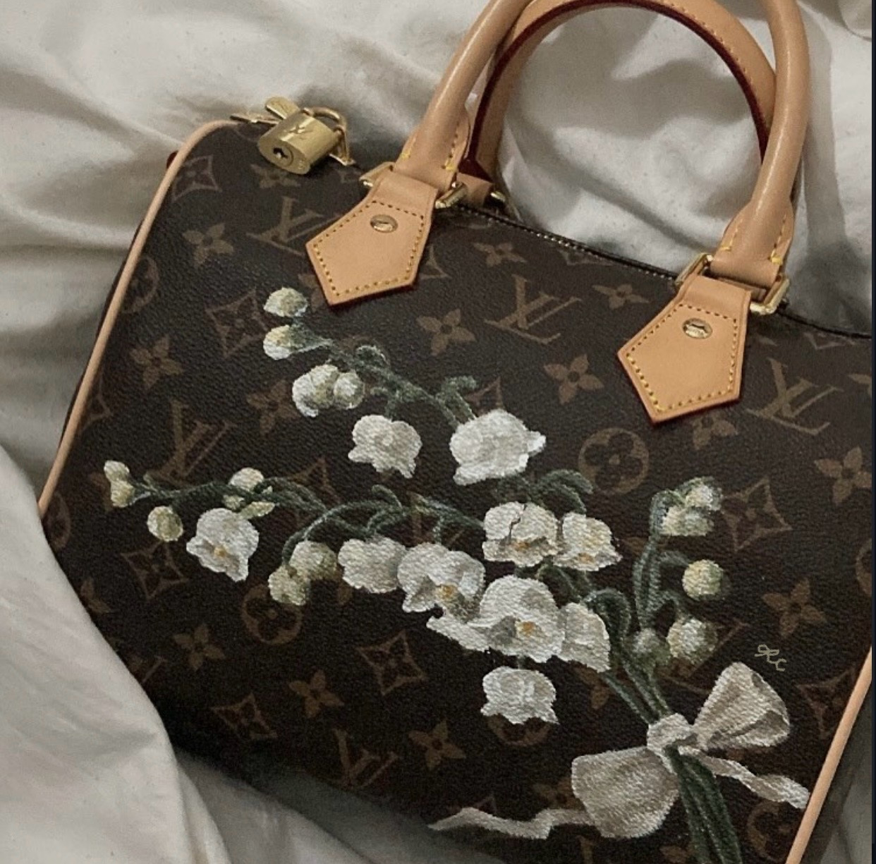 Painted floral design with pale blossoms across a dark tote bag.