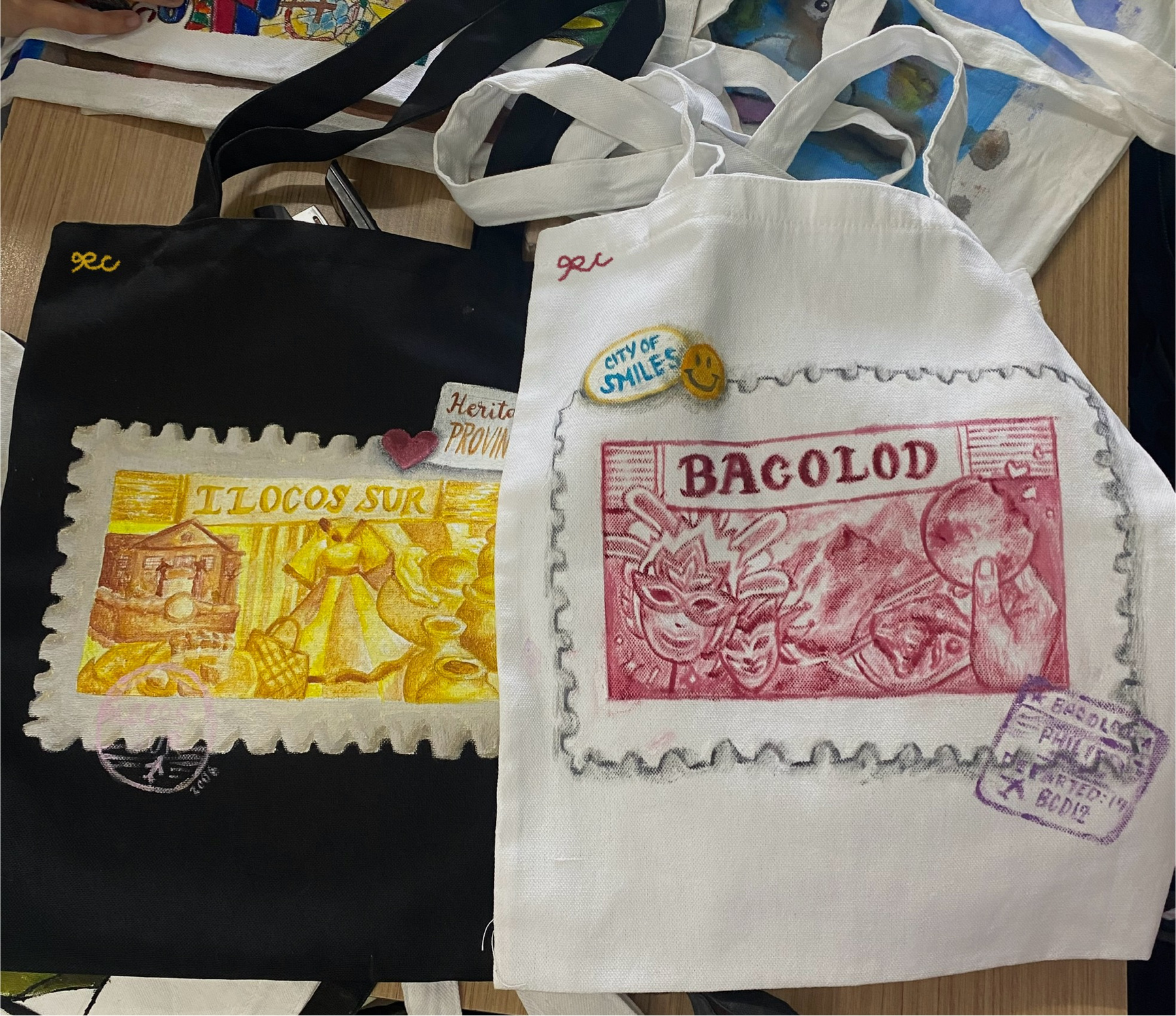 Two decorated tote bags photographed together on a work surface.