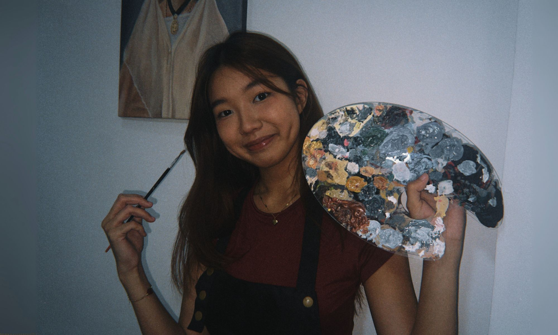 Xiamara holding a paint palette and brush.