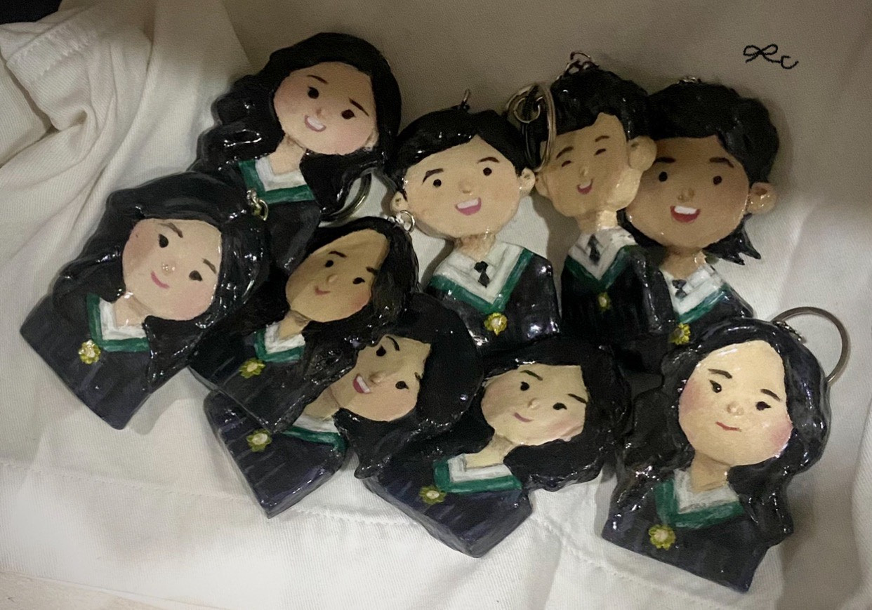 Group of painted clay portrait keychains arranged on a white surface.